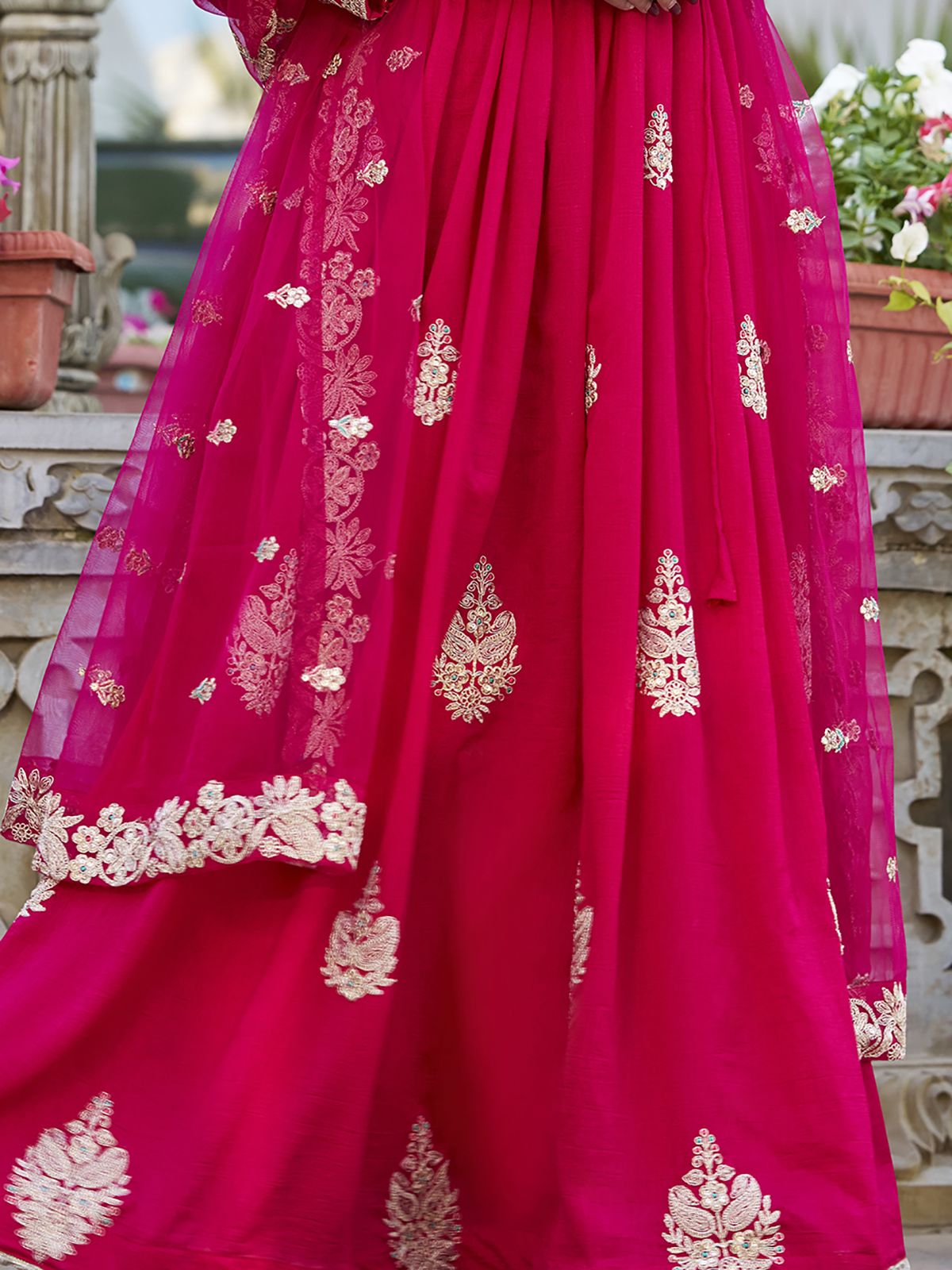 Anwitha Pink Embroidered Silk Anarkali Gown Set, crafted from luxurious Vichitra Silk with intricate sequins and thread embroidery accented by delicate lace details. This fully stitched Anarkali gown features a 3-meter flair and a soft cotton lining for comfort. Paired with a graceful net dupatta adorned with sequins embroidery and a lace border, this elegant ensemble is perfect for weddings, festive occasions, and grand celebrations