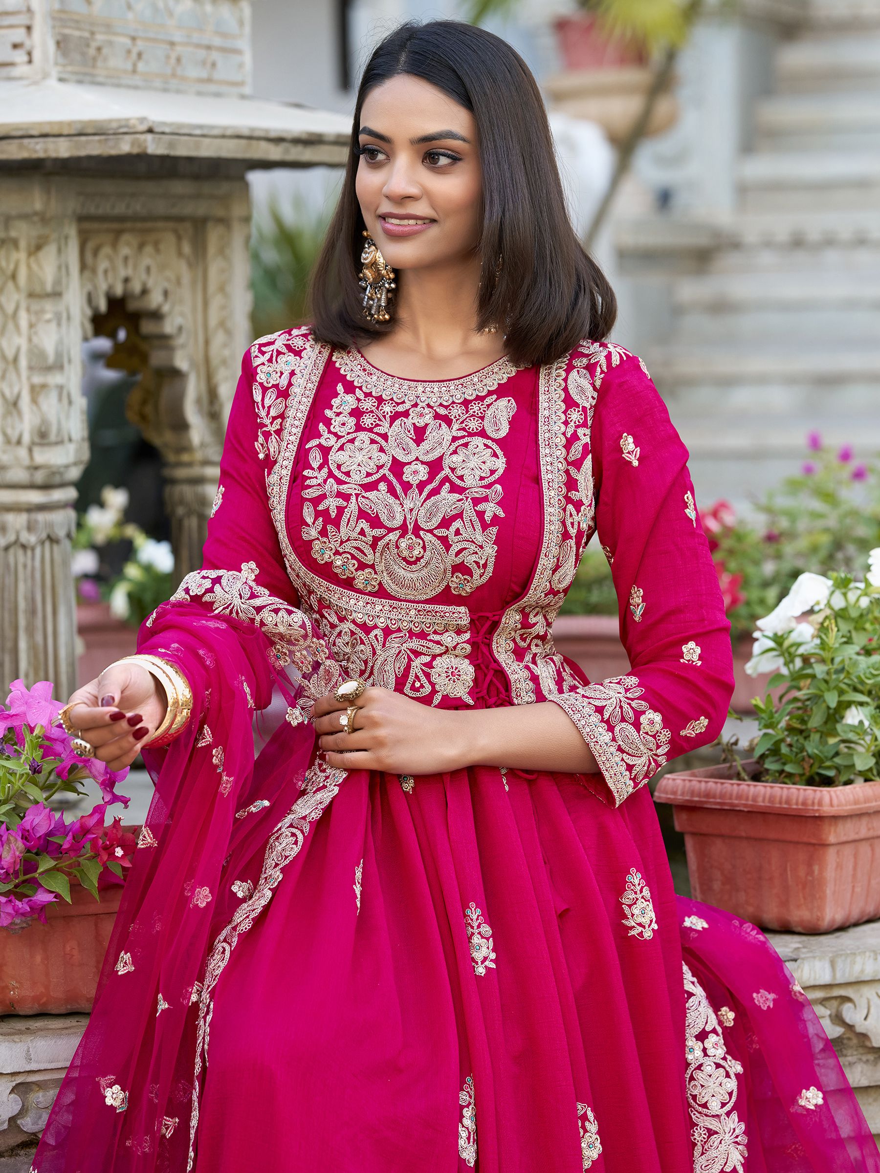Anwitha Pink Embroidered Silk Anarkali Gown Set, crafted from luxurious Vichitra Silk with intricate sequins and thread embroidery accented by delicate lace details. This fully stitched Anarkali gown features a 3-meter flair and a soft cotton lining for comfort. Paired with a graceful net dupatta adorned with sequins embroidery and a lace border, this elegant ensemble is perfect for weddings, festive occasions, and grand celebrations