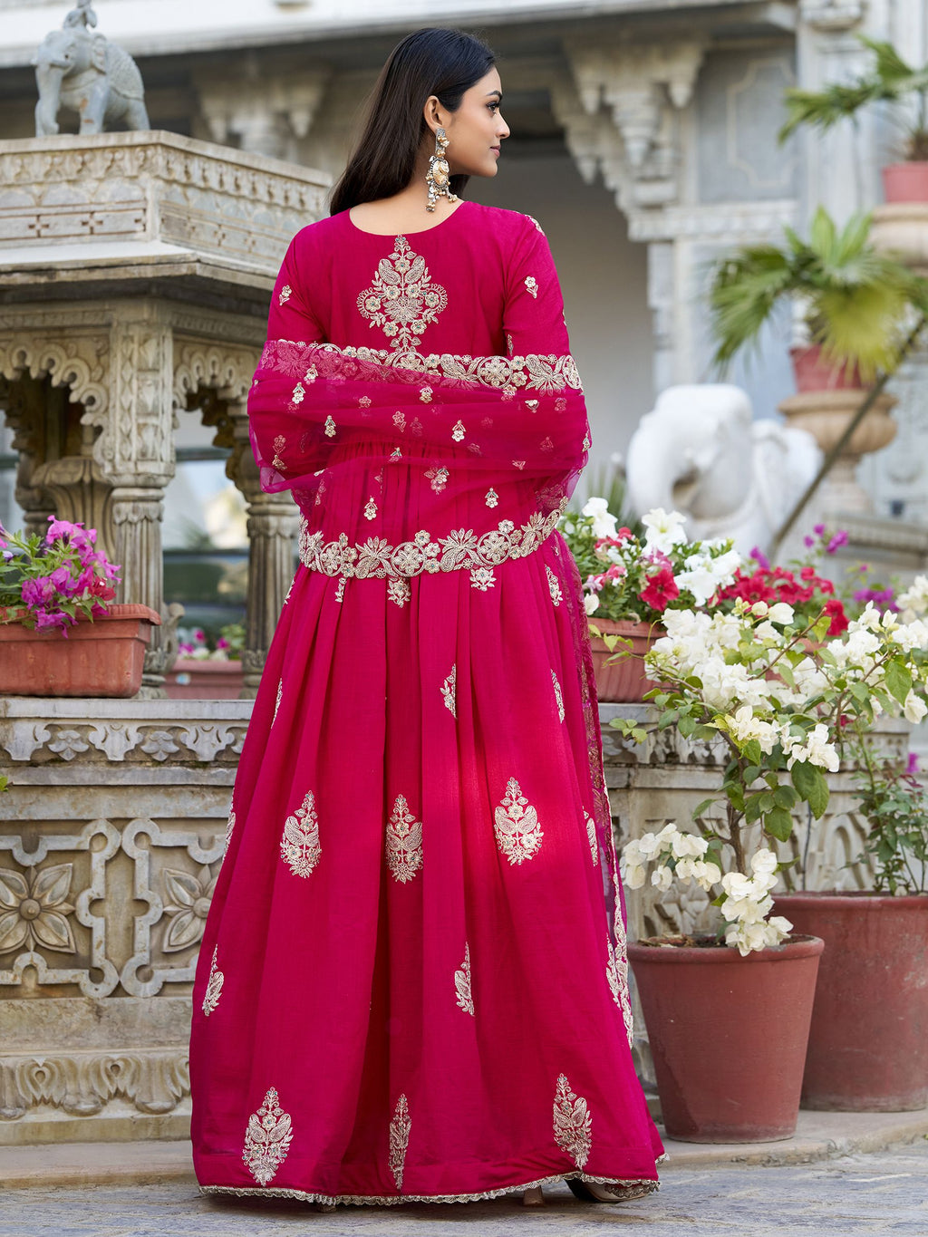 Anwitha Pink Embroidered Silk Anarkali Gown Set, crafted from luxurious Vichitra Silk with intricate sequins and thread embroidery accented by delicate lace details. This fully stitched Anarkali gown features a 3-meter flair and a soft cotton lining for comfort. Paired with a graceful net dupatta adorned with sequins embroidery and a lace border, this elegant ensemble is perfect for weddings, festive occasions, and grand celebrations