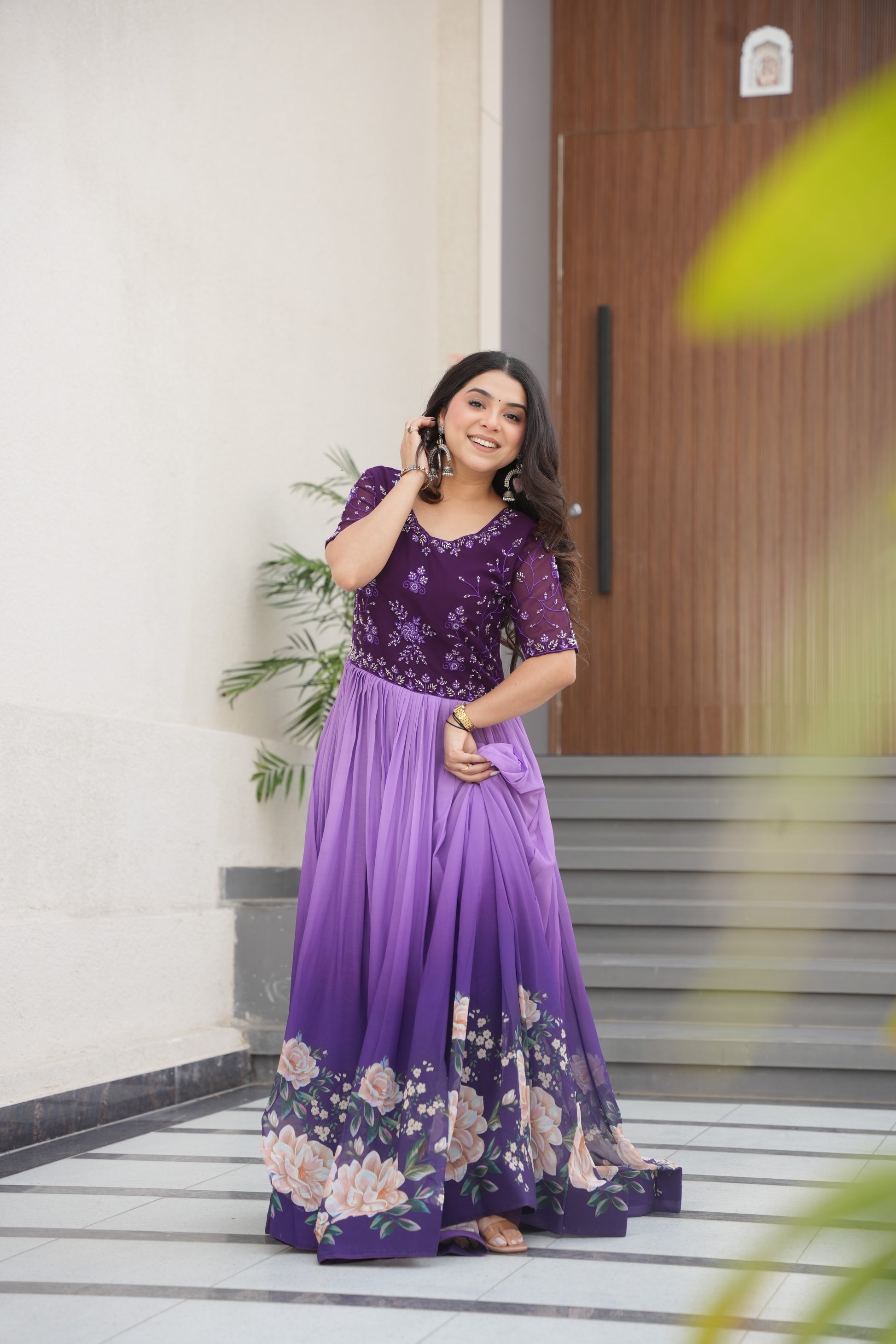 Hemrika Purple Embroidered Gown – elegant purple ethnic gown for women with floral print and beads embroidery, floor-length faux blooming gown, half sleeve gown with round neckline, canvas patta stitched Anarkali style gown, partywear gown for weddings and festive occasions, Indian designer gown with cotton lining, stylish readymade ethnic gown by Trinaari.