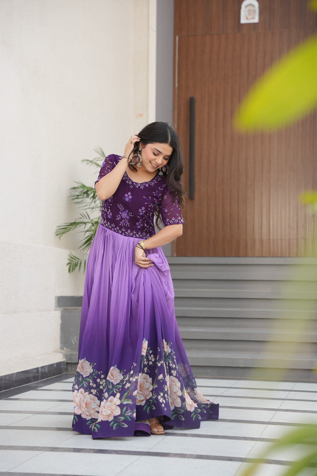 Hemrika Purple Embroidered Gown – elegant purple ethnic gown for women with floral print and beads embroidery, floor-length faux blooming gown, half sleeve gown with round neckline, canvas patta stitched Anarkali style gown, partywear gown for weddings and festive occasions, Indian designer gown with cotton lining, stylish readymade ethnic gown by Trinaari.