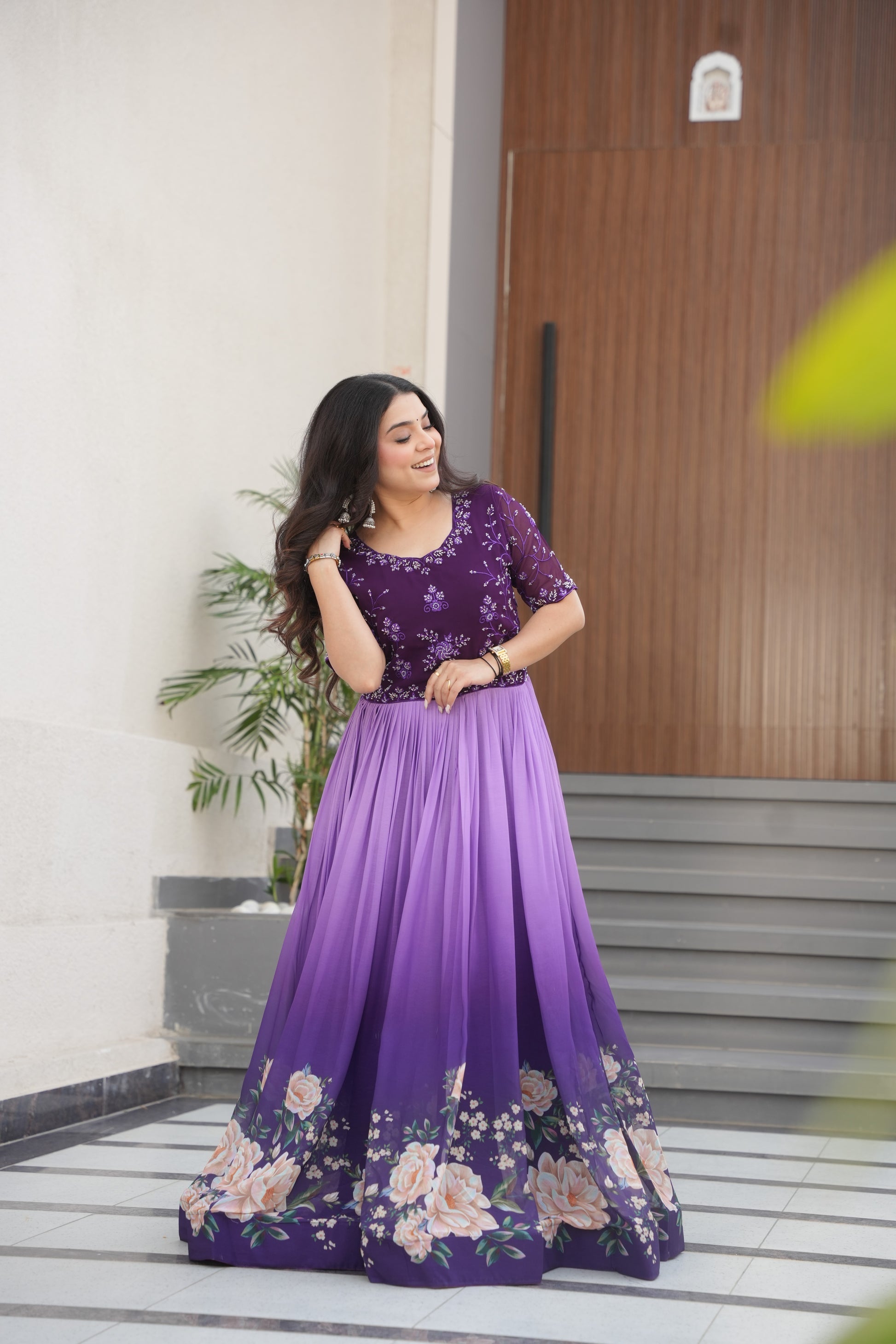 Hemrika Purple Embroidered Gown – elegant purple ethnic gown for women with floral print and beads embroidery, floor-length faux blooming gown, half sleeve gown with round neckline, canvas patta stitched Anarkali style gown, partywear gown for weddings and festive occasions, Indian designer gown with cotton lining, stylish readymade ethnic gown by Trinaari.