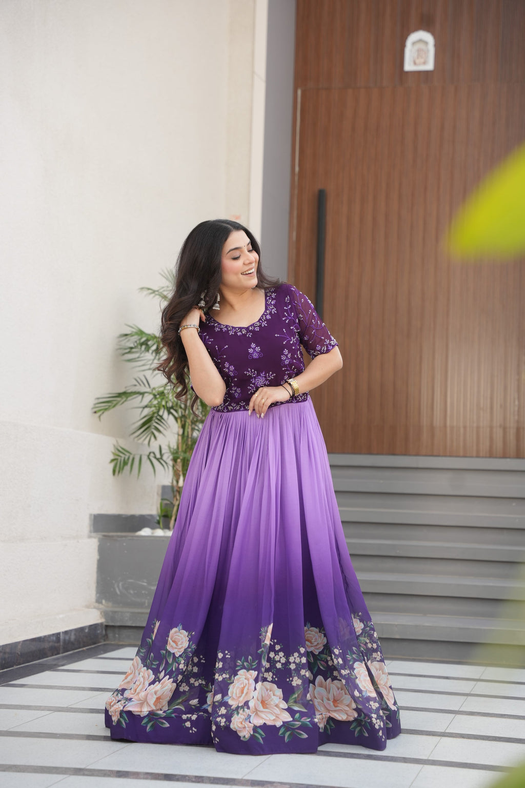 Hemrika Purple Embroidered Gown – elegant purple ethnic gown for women with floral print and beads embroidery, floor-length faux blooming gown, half sleeve gown with round neckline, canvas patta stitched Anarkali style gown, partywear gown for weddings and festive occasions, Indian designer gown with cotton lining, stylish readymade ethnic gown by Trinaari.