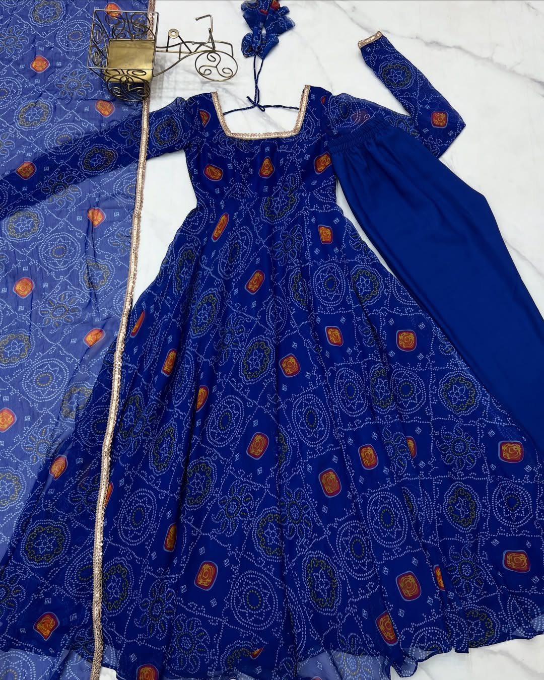 Shanvi Bandhej Chiffon Anarkali Suit Set – blue Bandhej Anarkali gown, traditional chiffon ethnic wear, women’s blue ethnic dress, Bandhej printed Anarkali for weddings, designer ethnic gown, Anarkali suit with lace dupatta, flair Anarkali with full sleeves, Bandhej print ethnic dress, blue festival wear gown, Indian wedding guest Anarkali.