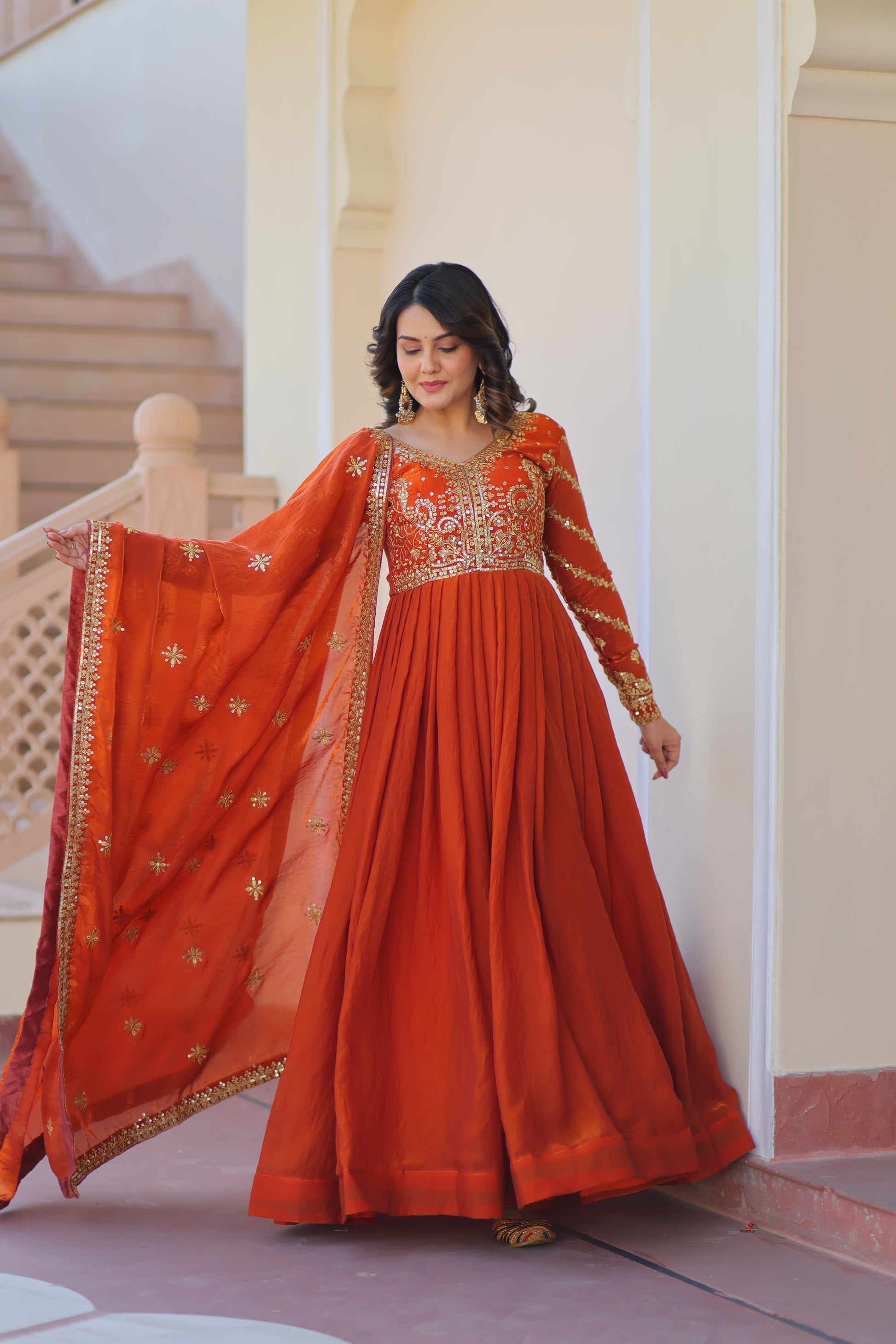 Varnita Orange Gown in Fendy Silk with zari & sequin work, full sleeves, V-neck & dupatta – regal festive wear, fully stitched.