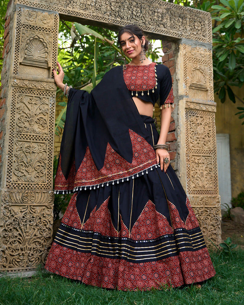 Woman in traditional black and red outfit standing in front of an ornate stone archway.