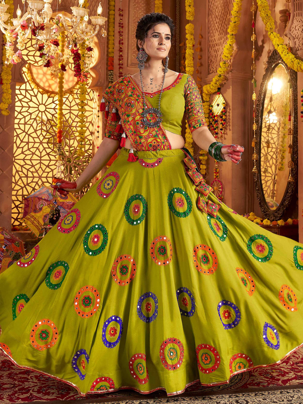 Woman in a colorful traditional outfit with intricate patterns in a decorated indoor setting.