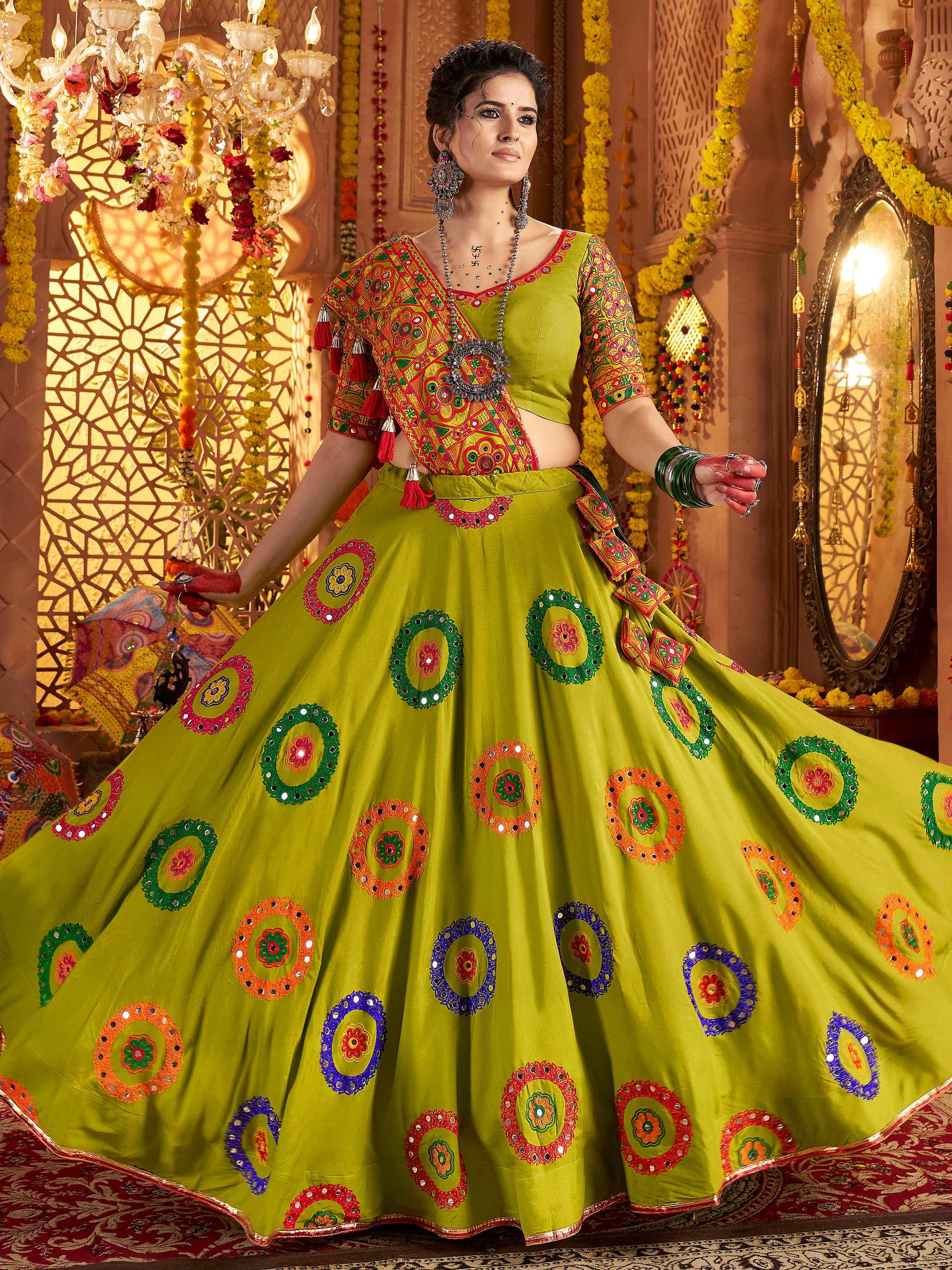 Woman in a colorful traditional outfit with intricate patterns in a decorated indoor setting.