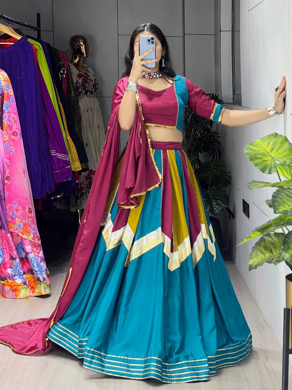 Person wearing a colorful traditional outfit with a vibrant background of clothing and decor.