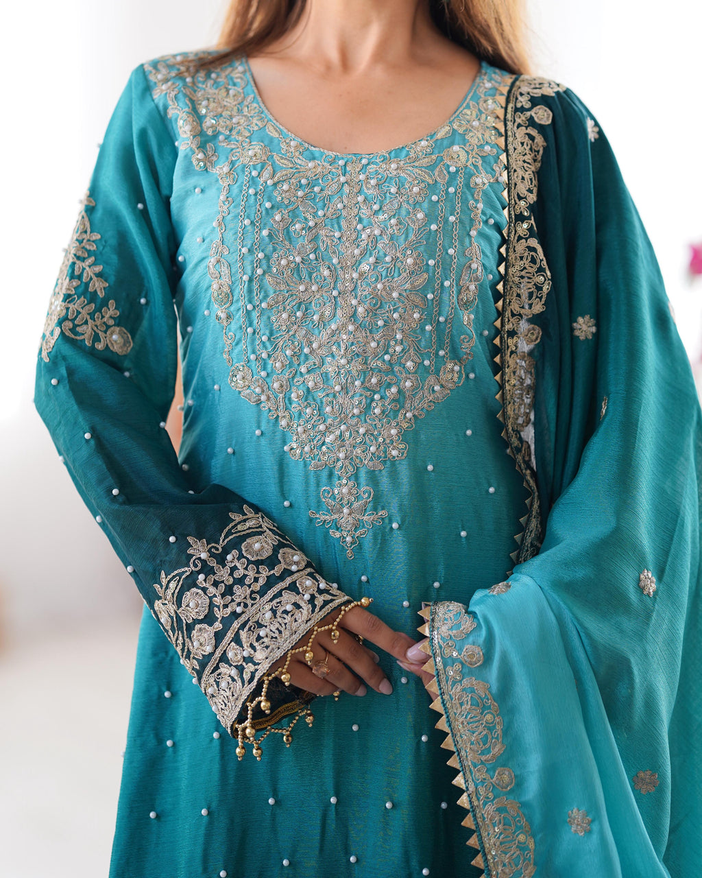 This Manvisha Teal Embroidered Sharara Suit Set is an exquisite choice for wedding wear, festive outfits, and partywear sharara suits. Crafted from premium Chinon silk, this designer sharara set features intricate cording dori embroidery, sequins work, and rivet moti detailing, making it an elegant addition to any ethnic wardrobe. The fully stitched embroidered kurta with front and back detailing pairs beautifully with designer sharara pants featuring an elastic waistband for comfort. Completing the ensembl