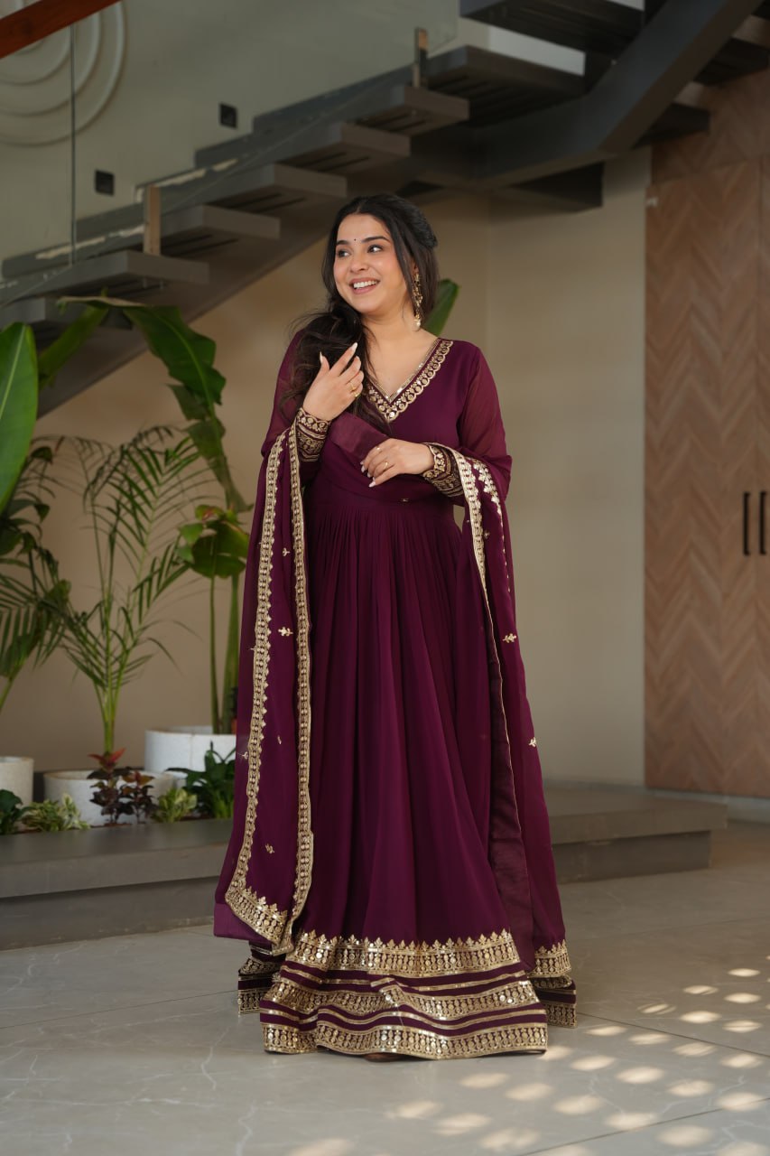Sampriti Wine Embroidered Gown Set – wine color gown with dupatta, zari sequin ethnic gown, faux blooming fabric gown for women, V-neck partywear gown, wedding guest long gown, Indian embroidered gown dress, full sleeve flair gown, bridal festive ethnic outfit, designer wine Anarkali gown, fully stitched traditional gown.