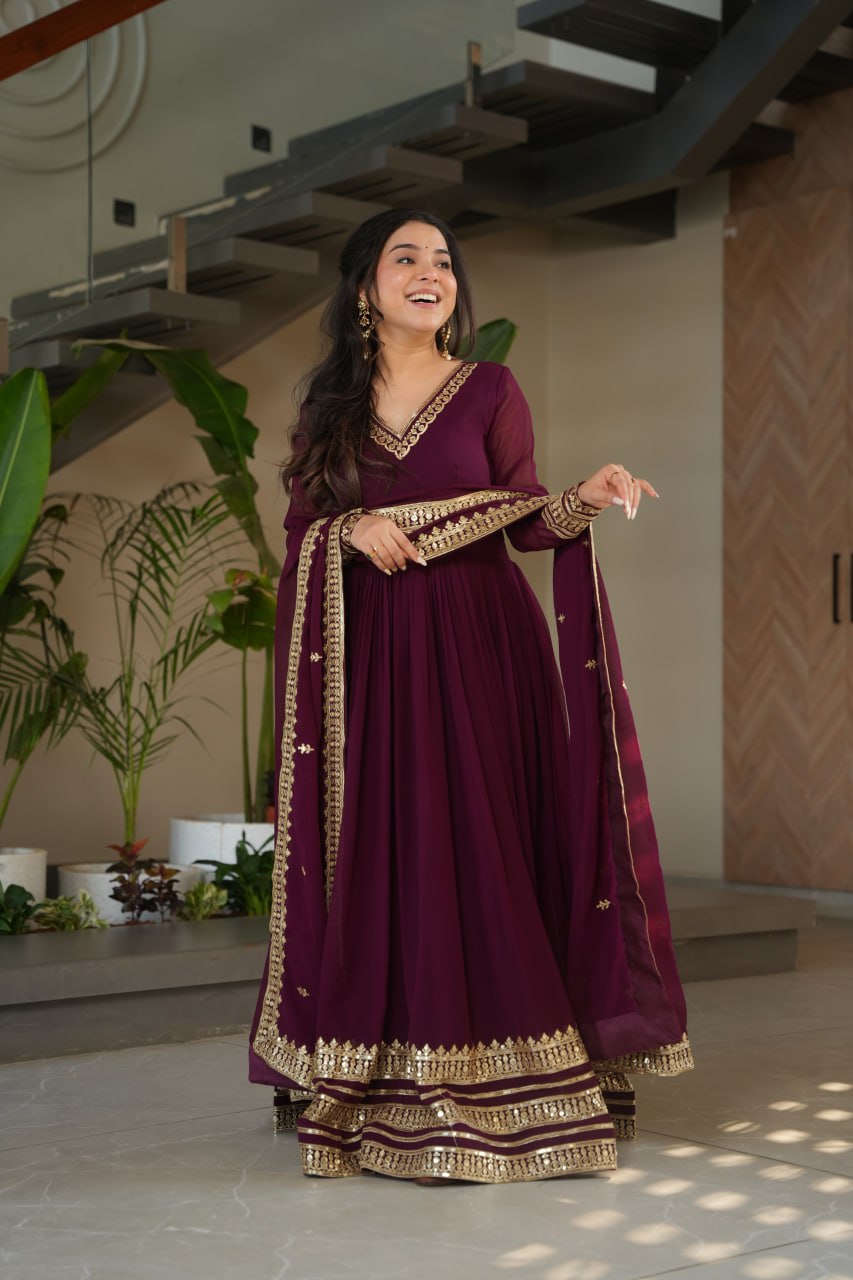 Sampriti Wine Embroidered Gown Set – wine color gown with dupatta, zari sequin ethnic gown, faux blooming fabric gown for women, V-neck partywear gown, wedding guest long gown, Indian embroidered gown dress, full sleeve flair gown, bridal festive ethnic outfit, designer wine Anarkali gown, fully stitched traditional gown.