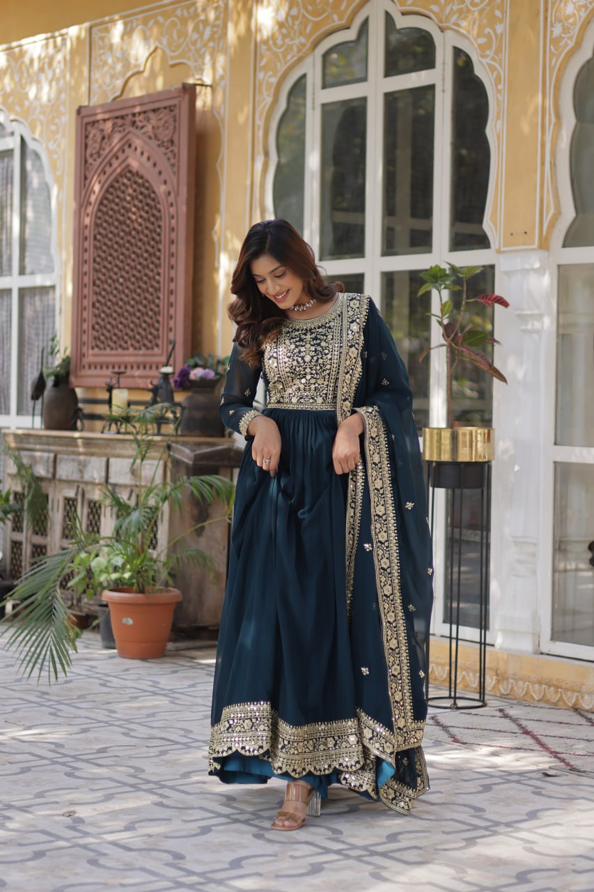  Suvarnita teal embroidered ethnic gown set with zari and sequin work, featuring full sleeves, round neck, flared 56-inch faux blooming gown and matching dupatta – ideal Indian party wear gown for weddings and festive occasions.