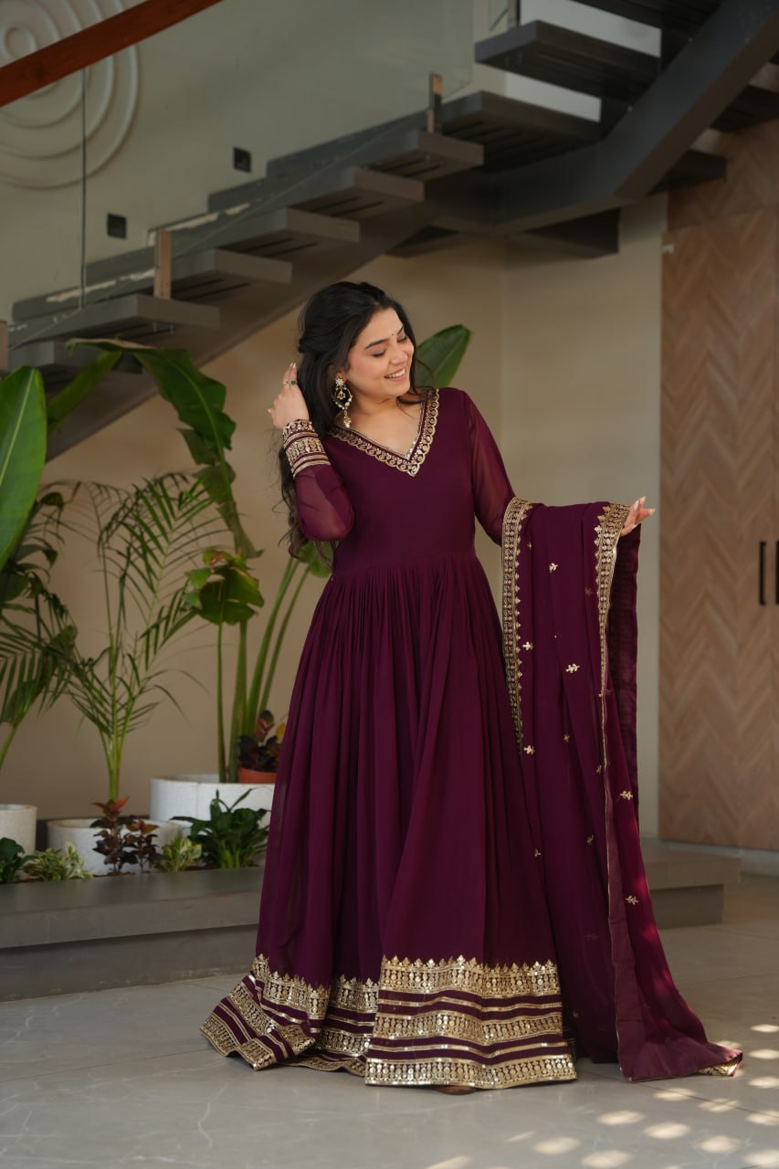 Sampriti Wine Embroidered Gown Set – wine color gown with dupatta, zari sequin ethnic gown, faux blooming fabric gown for women, V-neck partywear gown, wedding guest long gown, Indian embroidered gown dress, full sleeve flair gown, bridal festive ethnic outfit, designer wine Anarkali gown, fully stitched traditional gown.