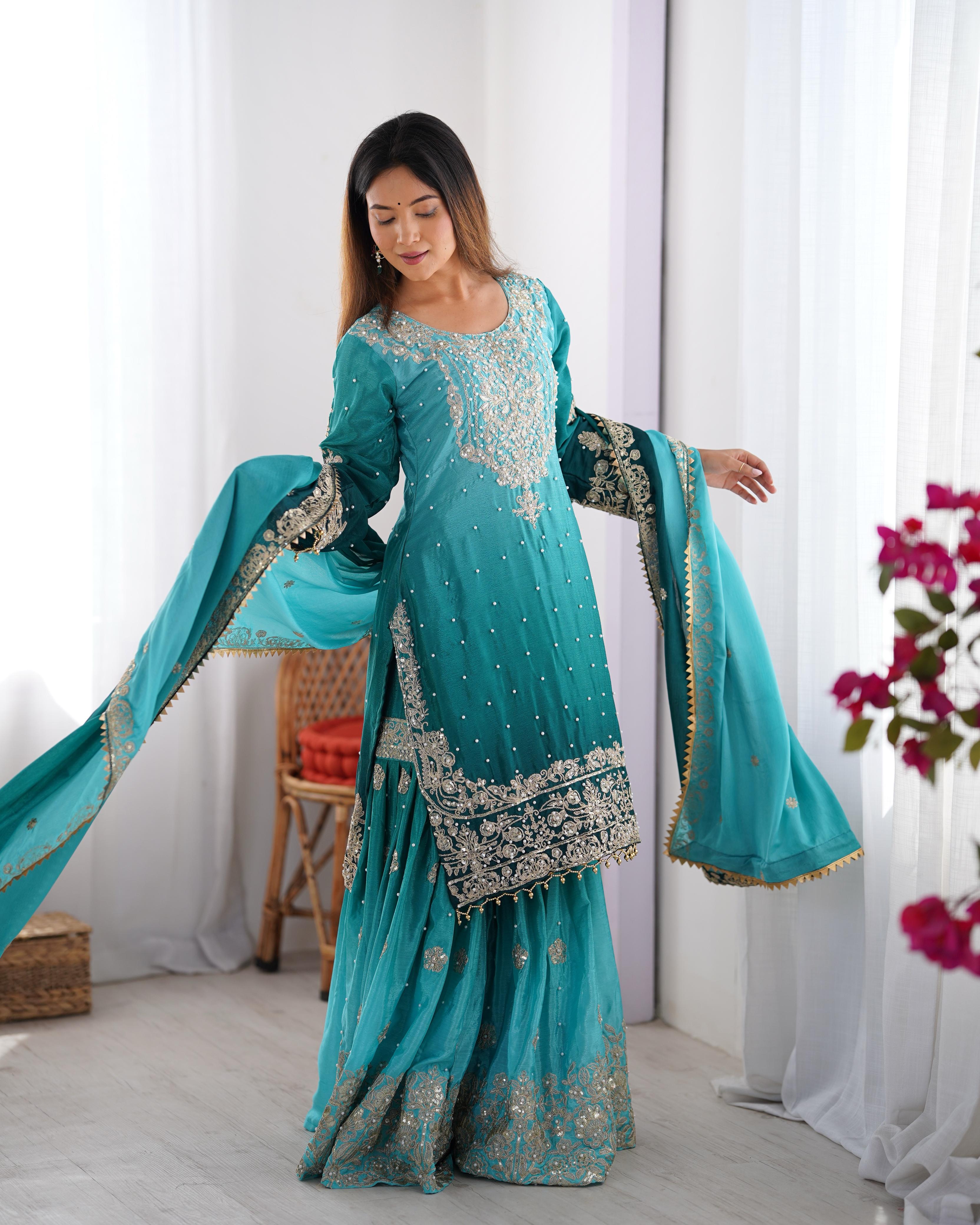 This Manvisha Teal Embroidered Sharara Suit Set is an exquisite choice for wedding wear, festive outfits, and partywear sharara suits. Crafted from premium Chinon silk, this designer sharara set features intricate cording dori embroidery, sequins work, and rivet moti detailing, making it an elegant addition to any ethnic wardrobe. The fully stitched embroidered kurta with front and back detailing pairs beautifully with designer sharara pants featuring an elastic waistband for comfort. Completing the ensembl